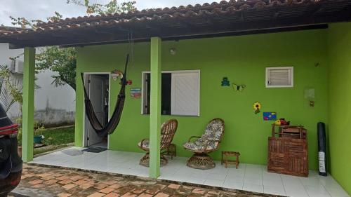 a green house with two chairs and a door at Chalé 15 Porto dos Lençóis in Barreirinhas