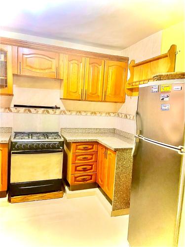 uma cozinha com armários de madeira e um frigorífico de aço inoxidável em Buena ventura house em San Luis