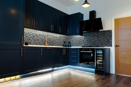 a blue kitchen with black cabinets and a television at Stunning flat in Brighton & Hove - Central luxury. in Brighton & Hove