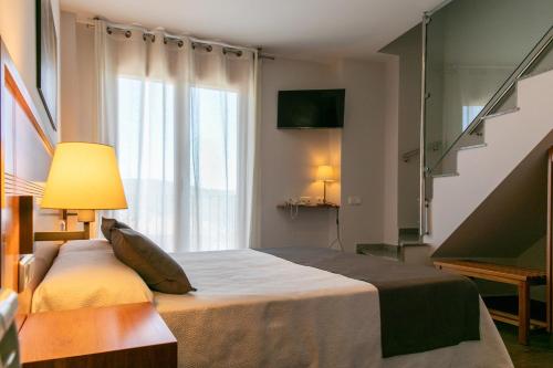 a bedroom with a bed with a lamp and a window at Aparthotel Cal Marçal in Puig-reig