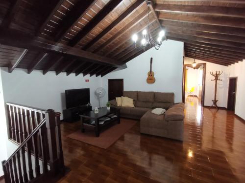 a living room with a couch and a guitar at Vila Mendonça in Povoação