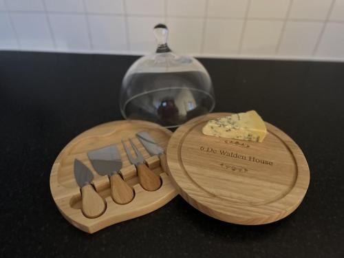two wooden cutting boards with utensils and a block of cheese at Studio flat in the heart of St. Johns Wood in London