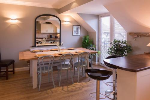 cocina con mesa con sillas y espejo en No 1 Kennington Court en Llandudno