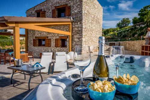 a table with glasses and a bottle of wine and chips at Villa Stone Walls with Jacuzzi in Castellammare del Golfo