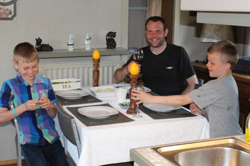 two boys standing around a table with a man holding a glass of wine at Spits-Lucie B&B in Izegem