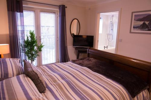 um quarto com uma cama, uma televisão e uma janela em No 1 Kennington Court em Llandudno