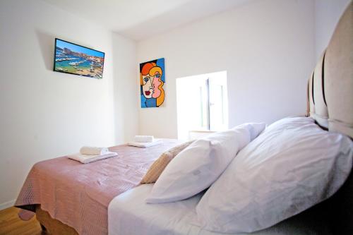 um quarto com uma cama com lençóis brancos em Actor Apartment em Čilipi