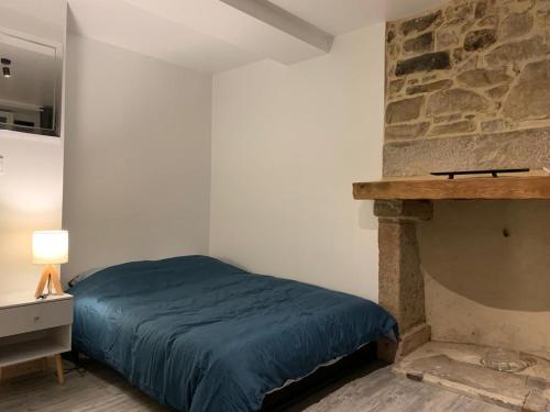 a bedroom with a bed and a stone fireplace at L'appart du bourg - 4 chambres lits doubles - sur 2 niveaux - 2 salles de bain - séjour avec espace salon et cuisine équipée ouverte sur le séjour - in Beaumont-Hague