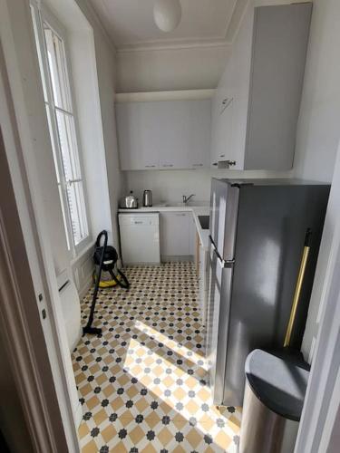 La cuisine est équipée d'un réfrigérateur noir et d'un sol en damier. dans l'établissement Appartement lumineux Art-déco centre-ville parking, à Bordeaux