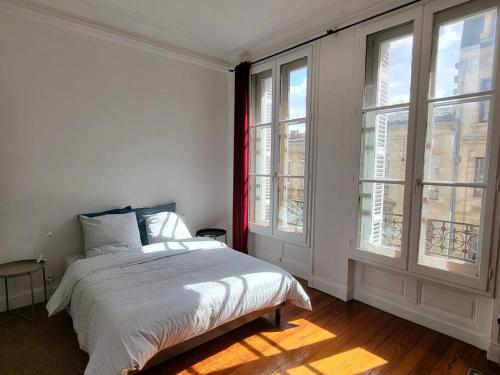 une chambre blanche avec un lit et deux fenêtres dans l'établissement Appartement lumineux Art-déco centre-ville parking, à Bordeaux