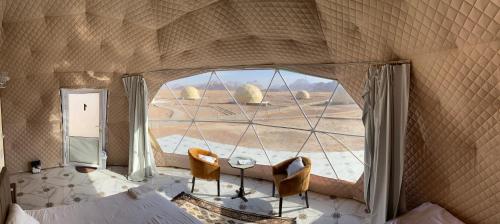 een kamer met een groot raam met een tafel en stoelen bij Katrina Rum camp in Wadi Rum