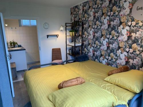 B&B slapen in de veenhoop في De Veenhoop: غرفة نوم بسريرين وجدار بالورود