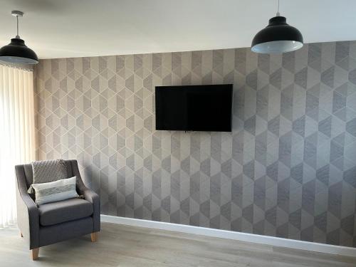 a room with a chair and a television on a wall at Chapel Court Apartments in Cannock