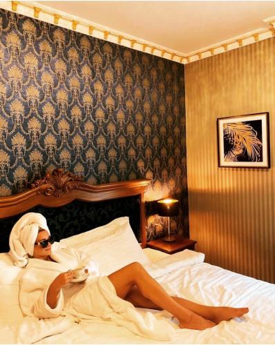 a woman laying on a bed in a hotel room at Envy Hotel in Durrës
