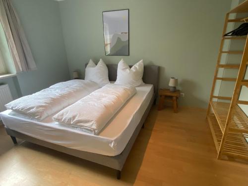 a bed with white pillows on it in a room at Bayern Lodge Bergen in Bergen