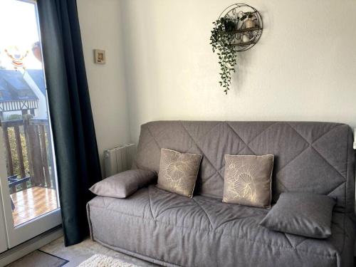 um sofá cinzento com almofadas numa sala de estar em Cabourg, appartement T2 accès direct mer em Cabourg