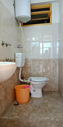 a bathroom with a toilet and a sink and a bucket at UpClimb Longstay for bus or taxi only guests in Manāli
