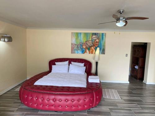 a large red bed in a room with a ceiling at Sun Room (Studio) on the edge of the Harties dam. in Hartbeespoort