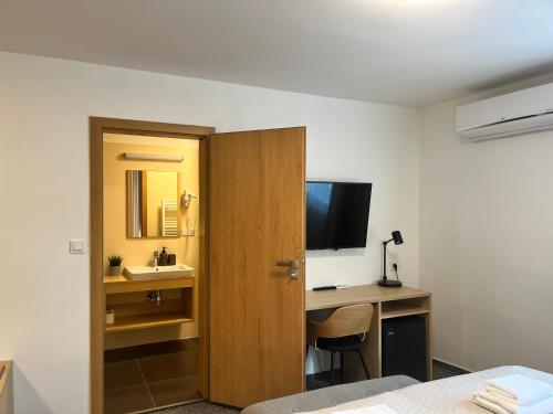 a hotel room with a desk and a television at Penzion U Halmů in Hustopeče