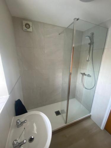 a bathroom with a shower and a white sink at Chapel Court Apartments in Cannock