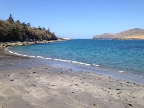 a beach with the ocean and mountains in the background at Geraldine House in Valentia Island
