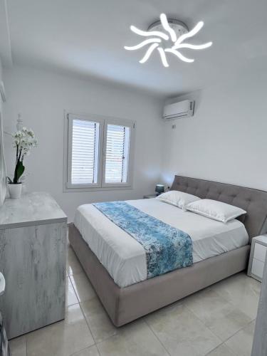a white bedroom with a large bed and a chandelier at White Luxury in Shkodër