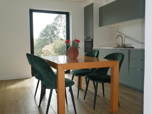 une cuisine avec une table en bois et des chaises vertes dans l'établissement Villa Kerandraon, à Gouesnach