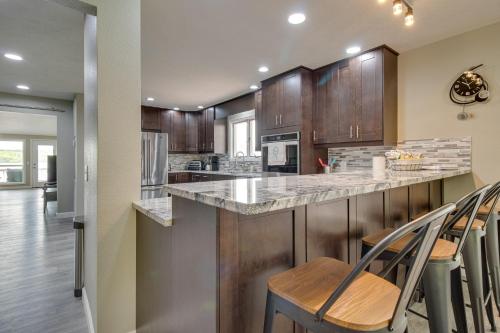 a kitchen with wooden cabinets and a counter with chairs at Serene Lakefront Mountain Home Getaway with Atrium! in Mountain Home