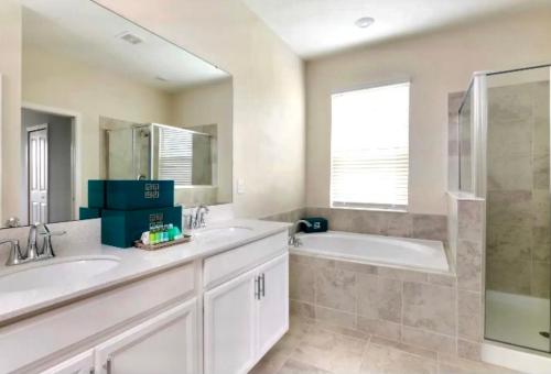 a bathroom with two sinks and a tub and a mirror at Luxury Champions Gate Condo-Disney Firework Views! in Kissimmee