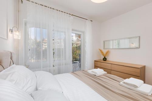 a white bedroom with a bed and a window at Apartman Marina in Vrbnik