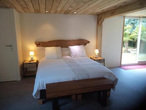 um quarto com uma cama com uma cabeceira de madeira e 2 candeeiros em La Canette de Phil - Chambre d'hôtes - Hébergement indépendant - vue sur piscine em Samatan