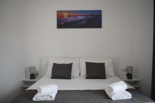 - un lit blanc avec deux oreillers et une photo sur le mur dans l'établissement Sunset Cottage 1, à Ksamil