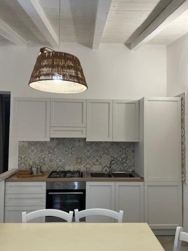 a kitchen with white cabinets and a table with a light at Appartamento il Caracolo a Cala Francese in La Maddalena