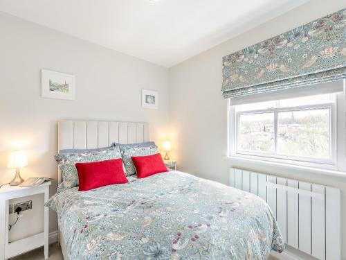 Un dormitorio con una cama con almohadas rojas y una ventana en Annes Cottage en Strines