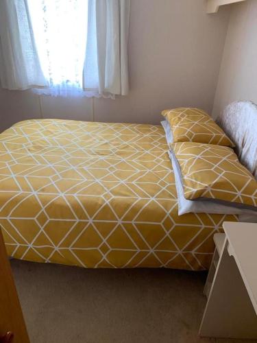 a bed with a yellow and white bedspread in a room at Sealands in Ingoldmells