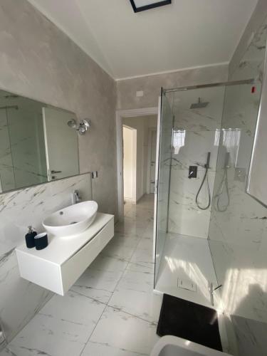 bagno bianco con lavandino e doccia di Casa SoSò a Massa