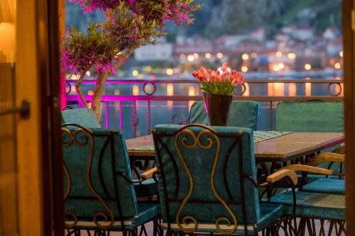 a table with chairs and a vase of flowers on a balcony at Villa Sun Castle in Kotor