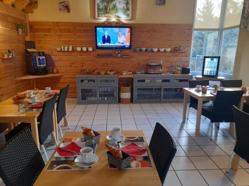 una sala da pranzo con tavoli e TV a parete di Hotel de l'Ile d'Amour a Langeac