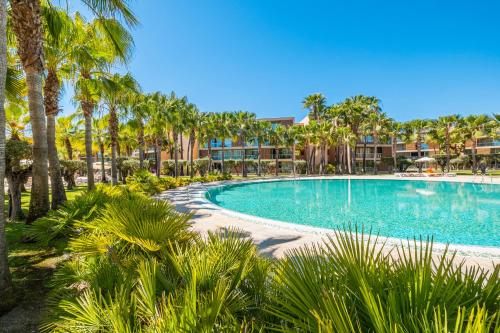 a swimming pool with palm trees in a resort at Apartment Salgados by Algarve Vacation in Albufeira