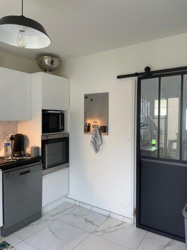 La cuisine est équipée de placards blancs et d'un four micro-ondes noir. dans l'établissement Maison 10/12 pers très proche circuit, au Mans