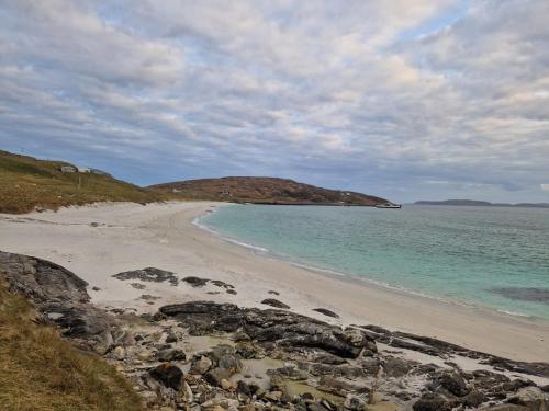 a beach with rocks and the ocean on a cloudy day at Loch an Eilean Pod Isle of South Uist in Pollachar