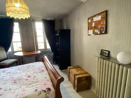 a bedroom with a bed and a table and windows at Chambre calme au cœur d’Ussel in Ussel