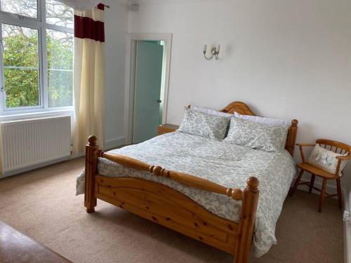 1 dormitorio con cama de madera y ventana en Serendipity, Tavistock, en Tavistock