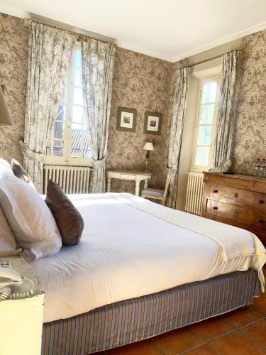 a bedroom with a bed and two windows at Hôtel la Magnaneraie in Villeneuve-lès-Avignon