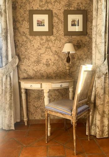 a chair sitting in front of a desk with a lamp at Hôtel la Magnaneraie in Villeneuve-lès-Avignon