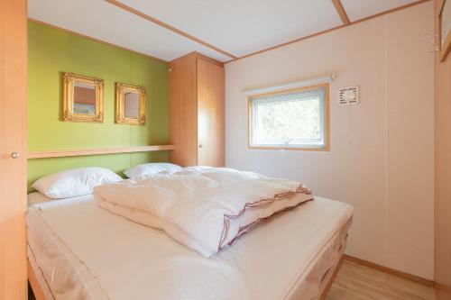 a bedroom with a bed with white sheets and a window at Heidehut in Midsland
