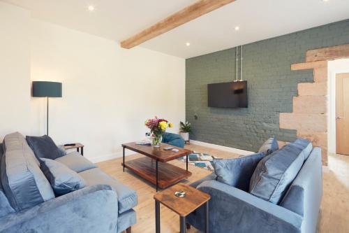 a living room with blue couches and a tv at Hayes Farm - 8 Houses in Gloucester