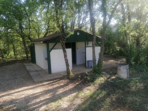 Emplacement tente camping car في Saint-Aubin-de-Nabirat: مبنى صغير ابيض واخضر في الغابة