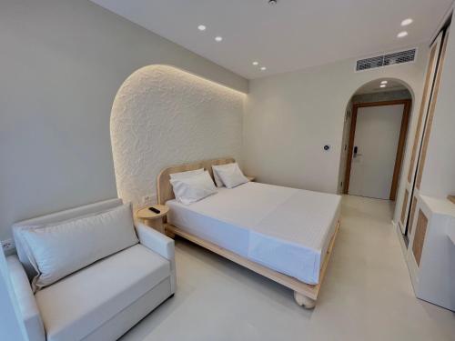 a white bedroom with a bed and a chair at Dimitri Hotel in Himare