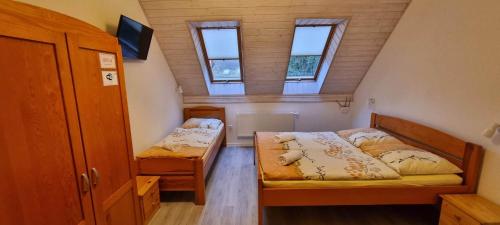 ポビエロボにあるPod Żaglamiのベッド2台と窓2つが備わる小さな客室です。